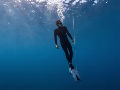 A freediver equalising while descending a guide rope