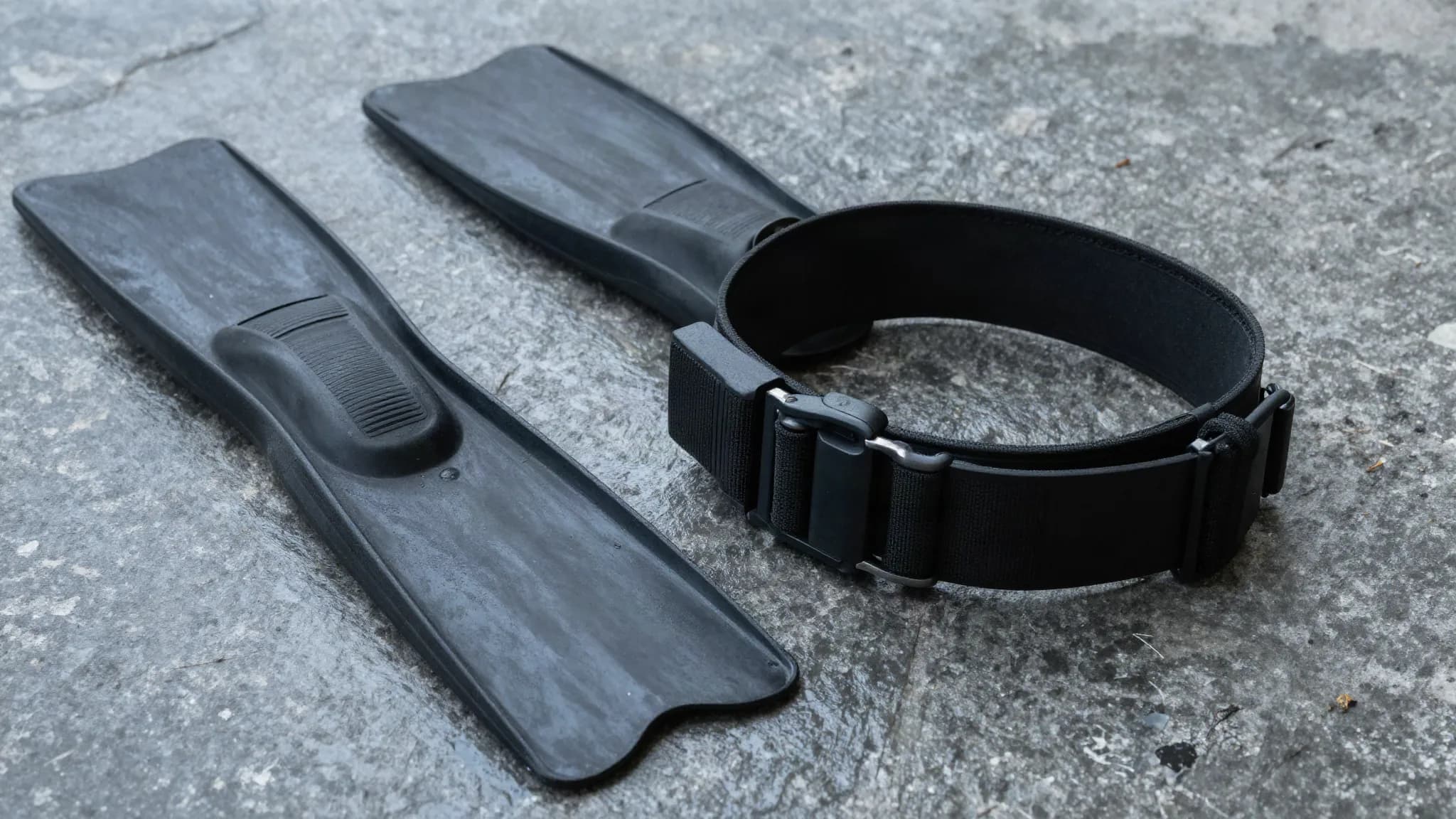 A rubber freediving weight belt with lead weights on wet stone