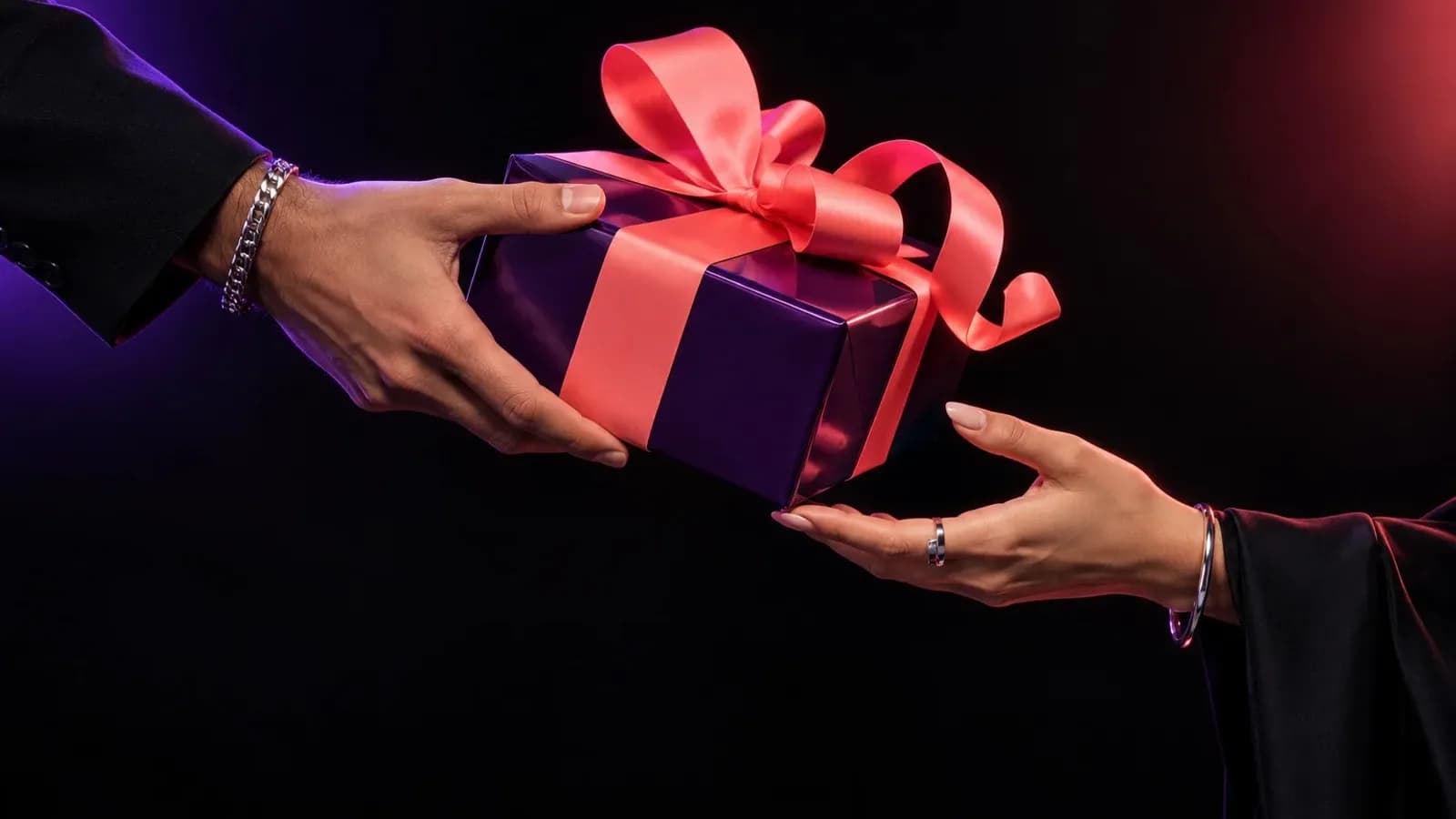 Two hands passing a purple gift box tied with a coral ribbon against a dark background, a Giftze campaign photograph supplied by the company