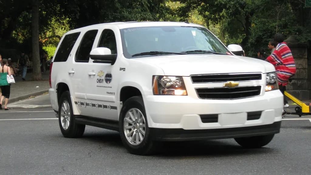 A white Chevrolet Tahoe hybrid sport utility vehicle driving past trees and pedestrians in New York City, photographed on 12 July 2008, a file photograph of a General Motors vehicle and not of any driver, app or data in the settlement