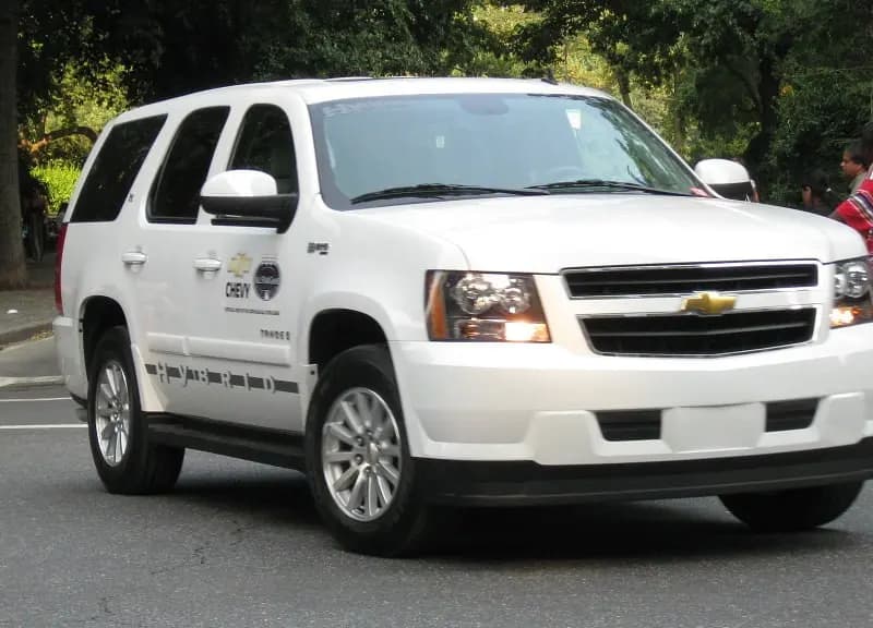 A white Chevrolet Tahoe hybrid sport utility vehicle driving past trees and pedestrians in New York City, photographed on 12 July 2008, a file photograph of a General Motors vehicle and not of any driver, app or data in the settlement