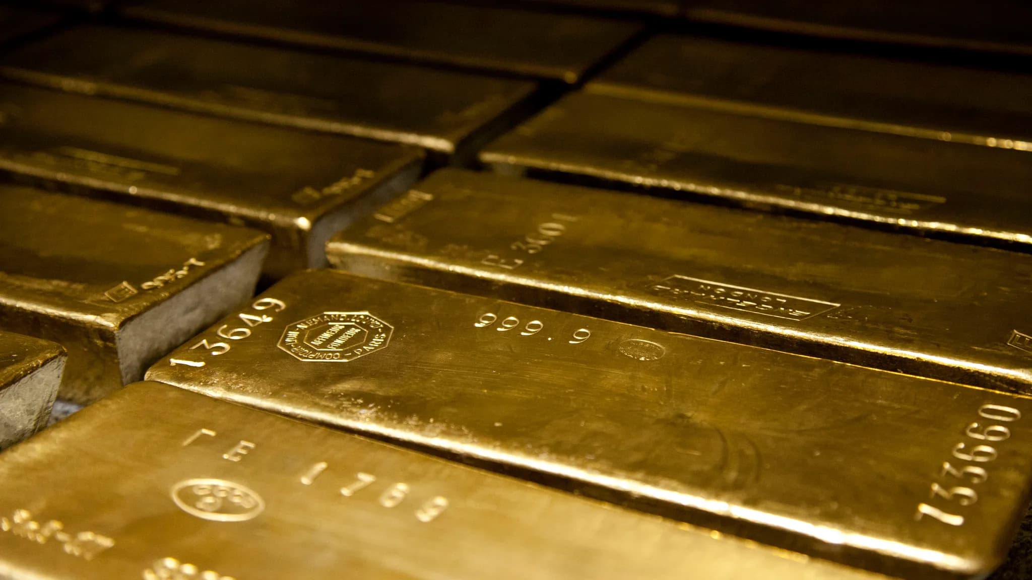 Gold bars beside a professional market chart showing a volatile second-half outlook