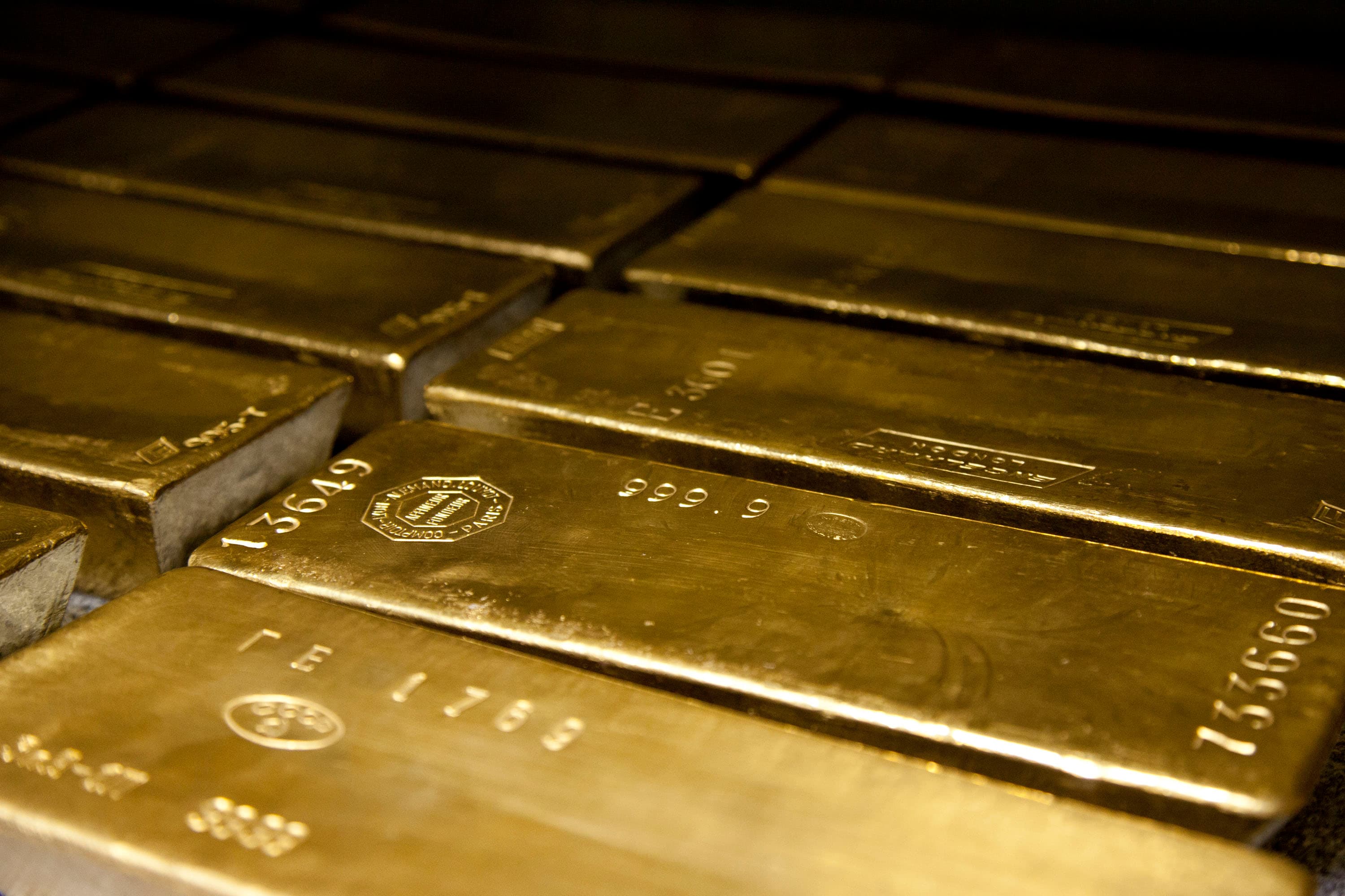 Gold bars beside a professional market chart showing a volatile second-half outlook