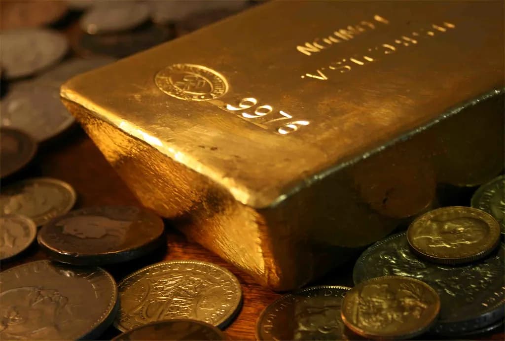 Gold bars beside a professional financial market display