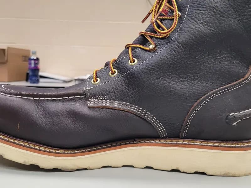 A leather work boot photographed from the side, the row of welt stitching visible along the ledge where the upper meets the sole