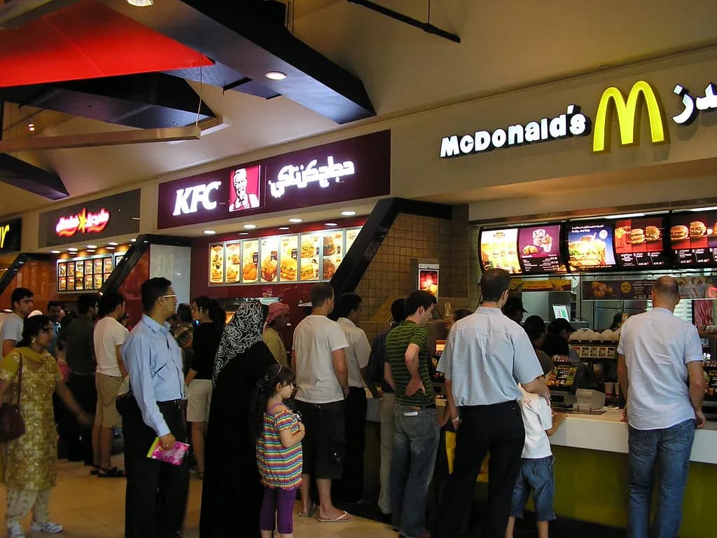 A busy food court counter in a Gulf shopping mall with diners queuing