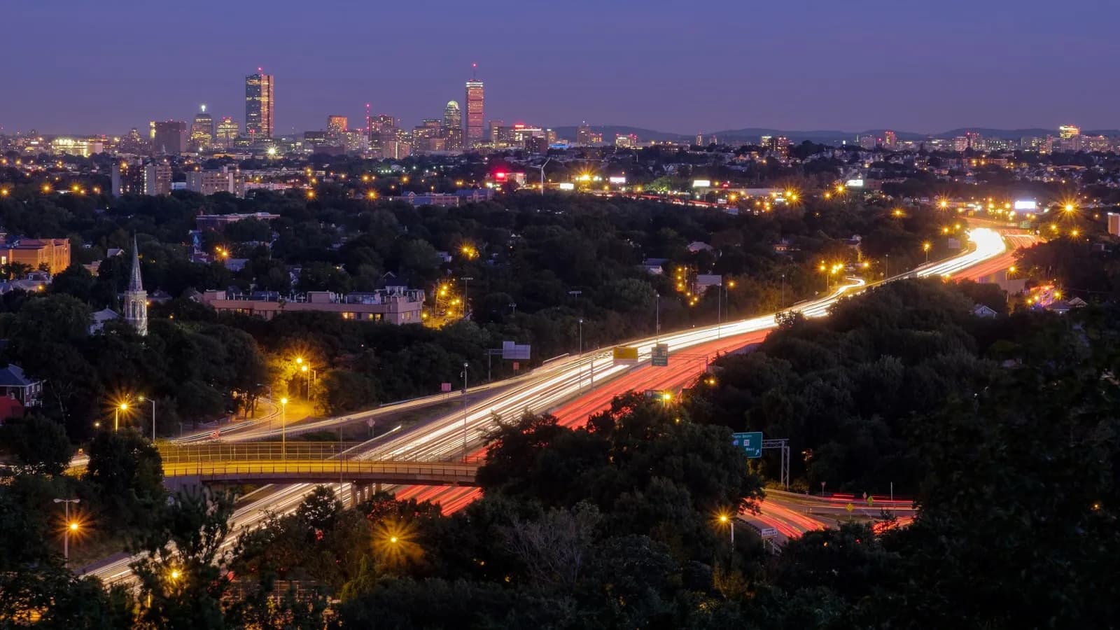 Evening traffic streaming along Interstate 93 north of Boston, with the city skyline behind, the road the air filtration trial was run beside
