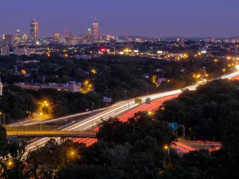 Evening traffic streaming along Interstate 93 north of Boston, with the city skyline behind, the road the air filtration trial was run beside