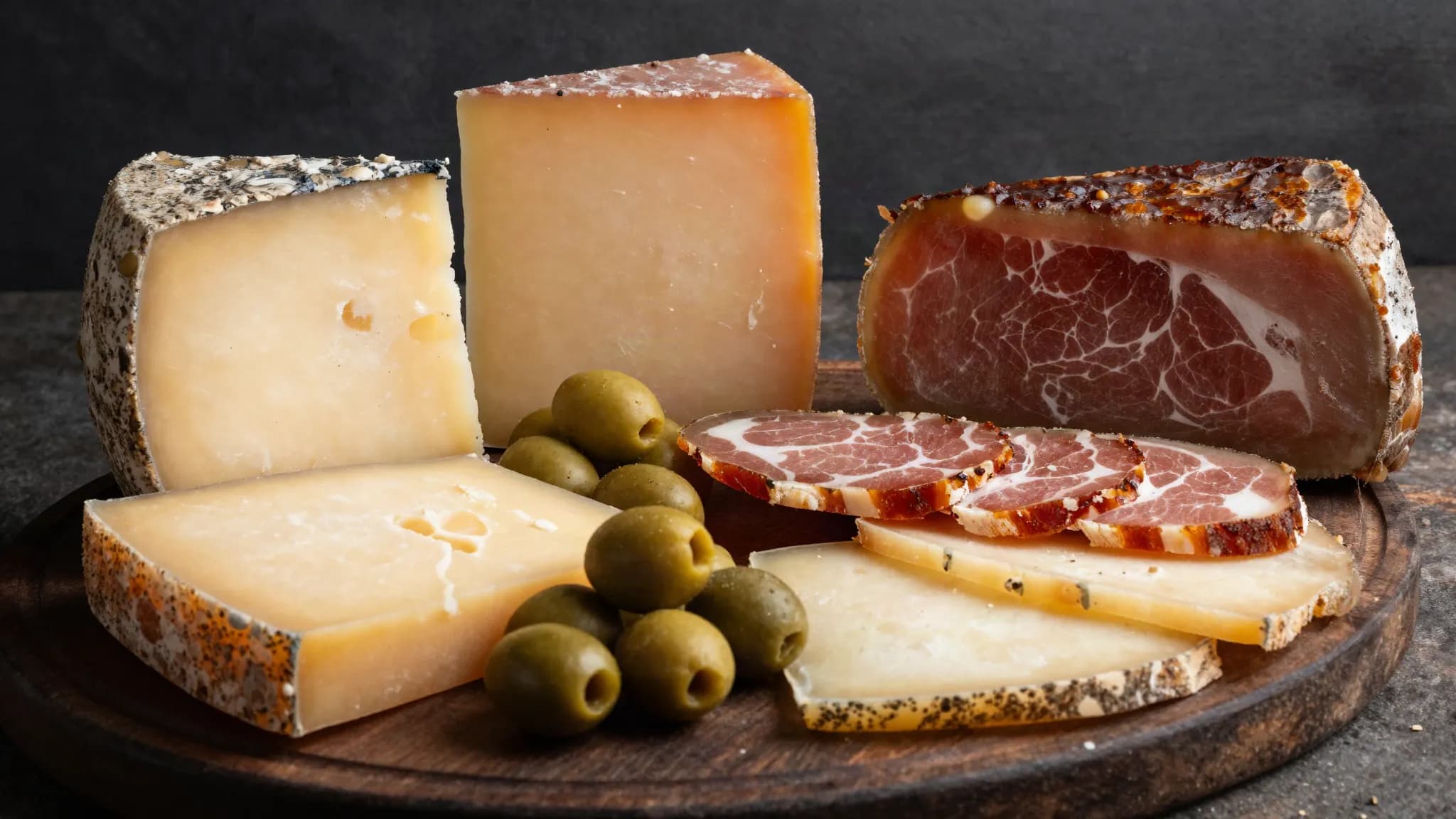 Aged cheese and cured meats on a dark wooden board