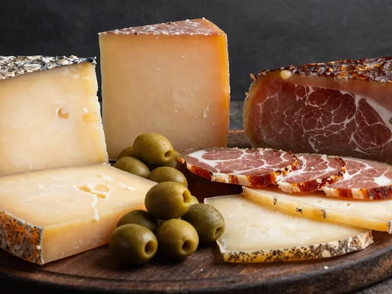 Aged cheese and cured meats on a dark wooden board