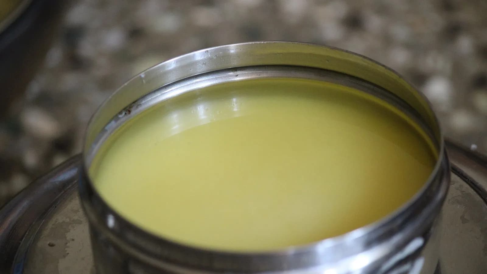 Homemade ghee cooling in a steel pot, clear and deep gold, with the browned milk solids already strained out