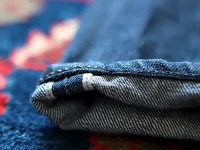The turned-up cuff of a pair of Tellason selvedge jeans showing the red-line self-finished edge, photographed in 2011