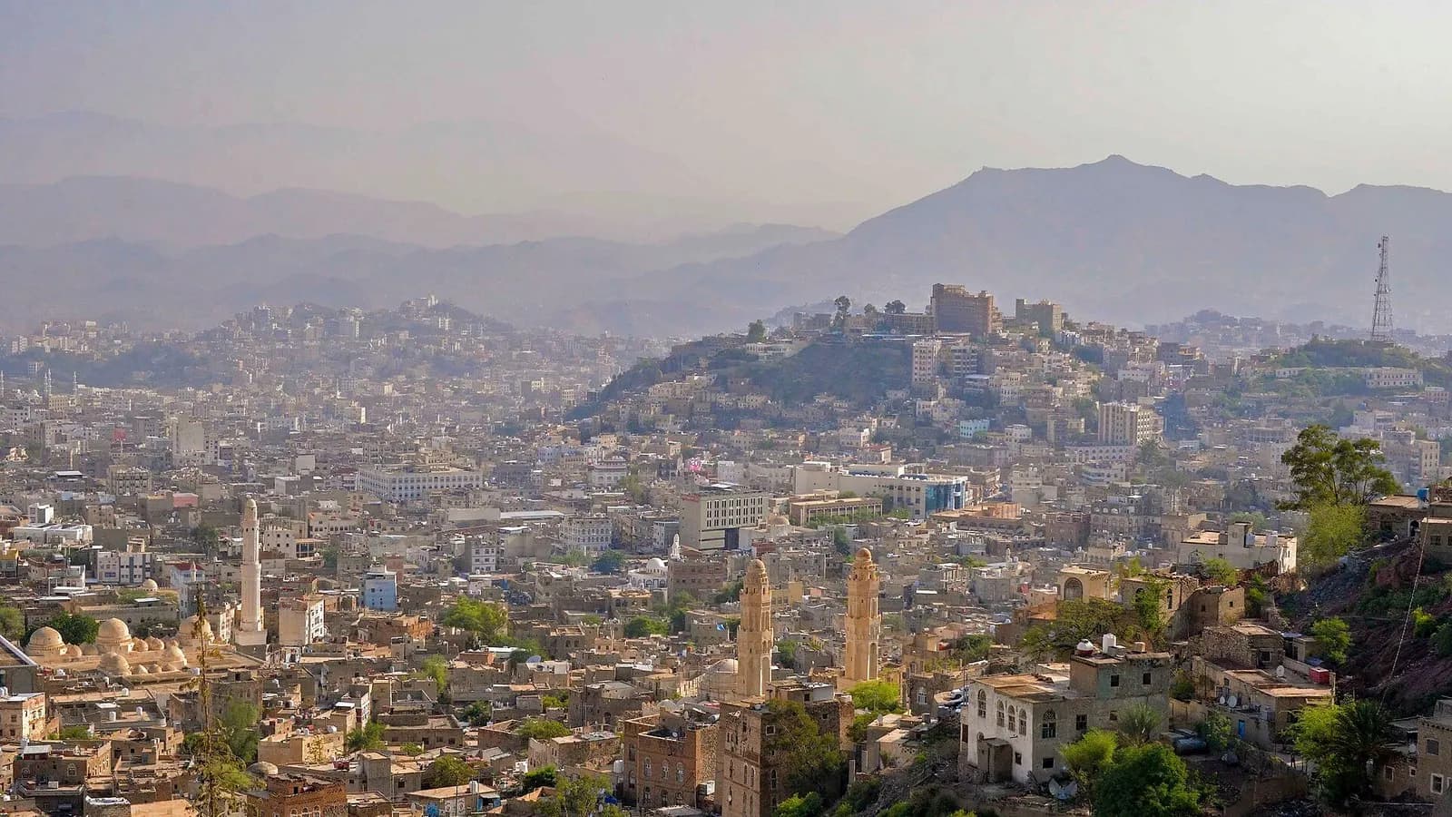 A hazy view over the crowded rooftops, minarets and hillside of the city of Taizz in Yemen under a pale sky, photographed on 18 August 2013, a file photograph of the city and not of the current siege or of any person affected