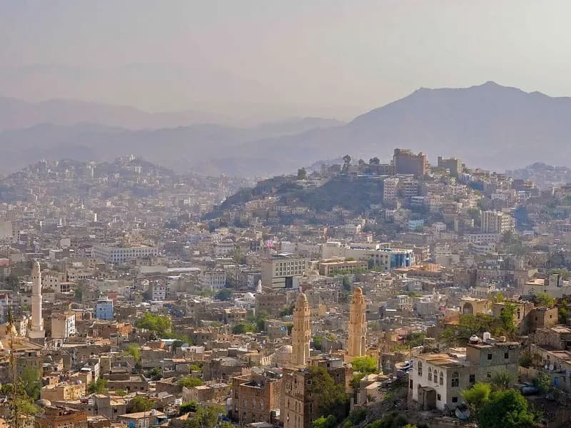 A hazy view over the crowded rooftops, minarets and hillside of the city of Taizz in Yemen under a pale sky, photographed on 18 August 2013, a file photograph of the city and not of the current siege or of any person affected