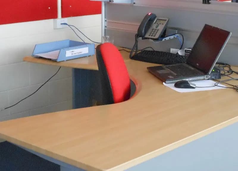 An empty office desk with a laptop and a telephone