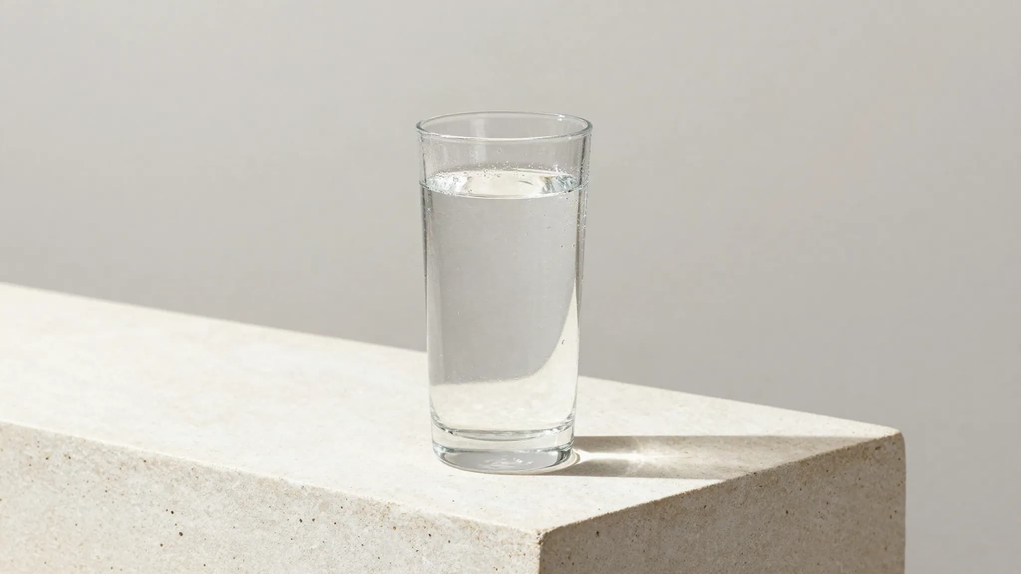 A glass of water with condensation on a stone counter