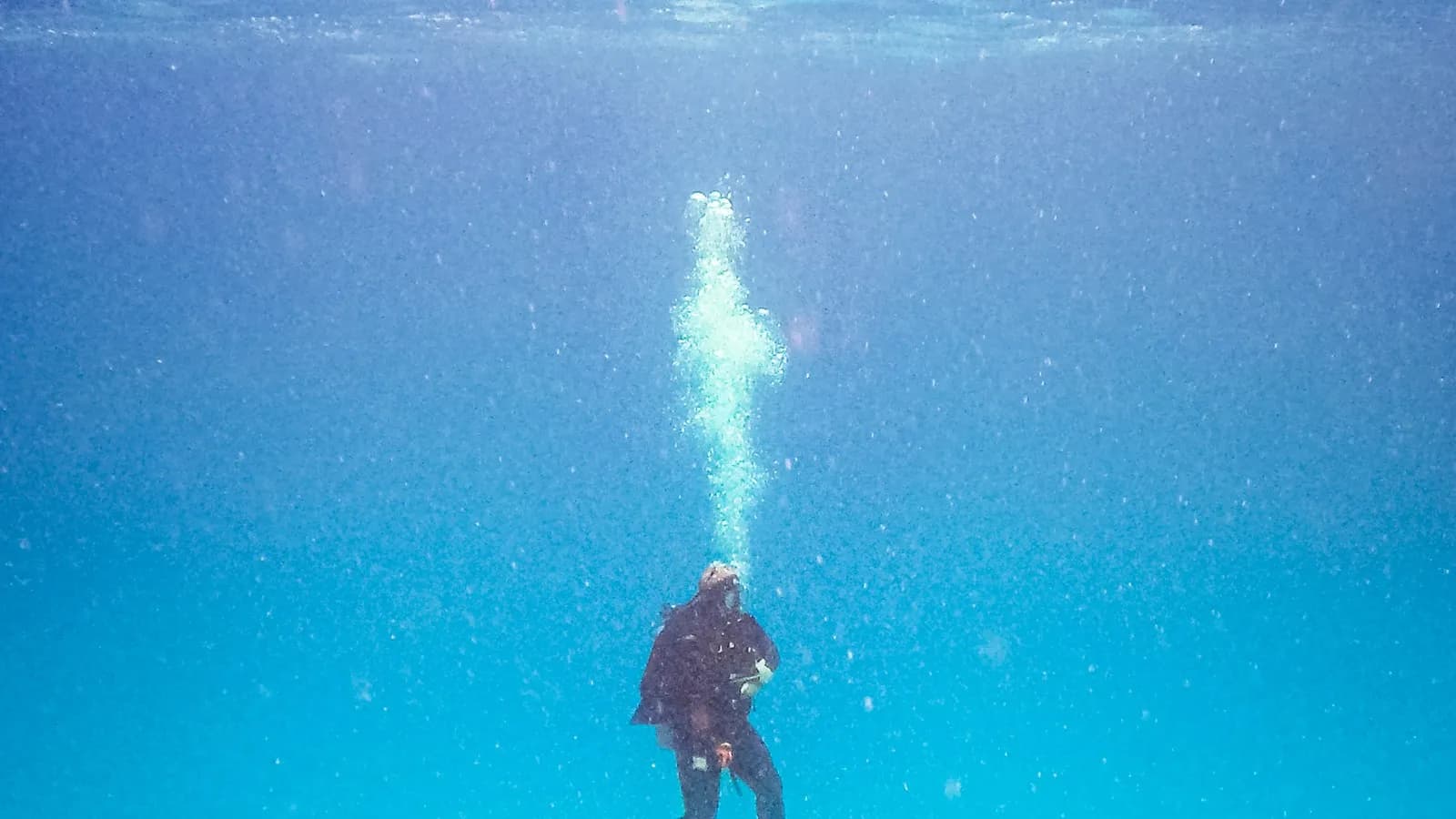 A scuba diver in a dark wetsuit rising through clear blue water with a column of bubbles above, photographed off Cozumel, Mexico, on 31 January 2016, a file photograph illustrative of diving and not of any case of the condition