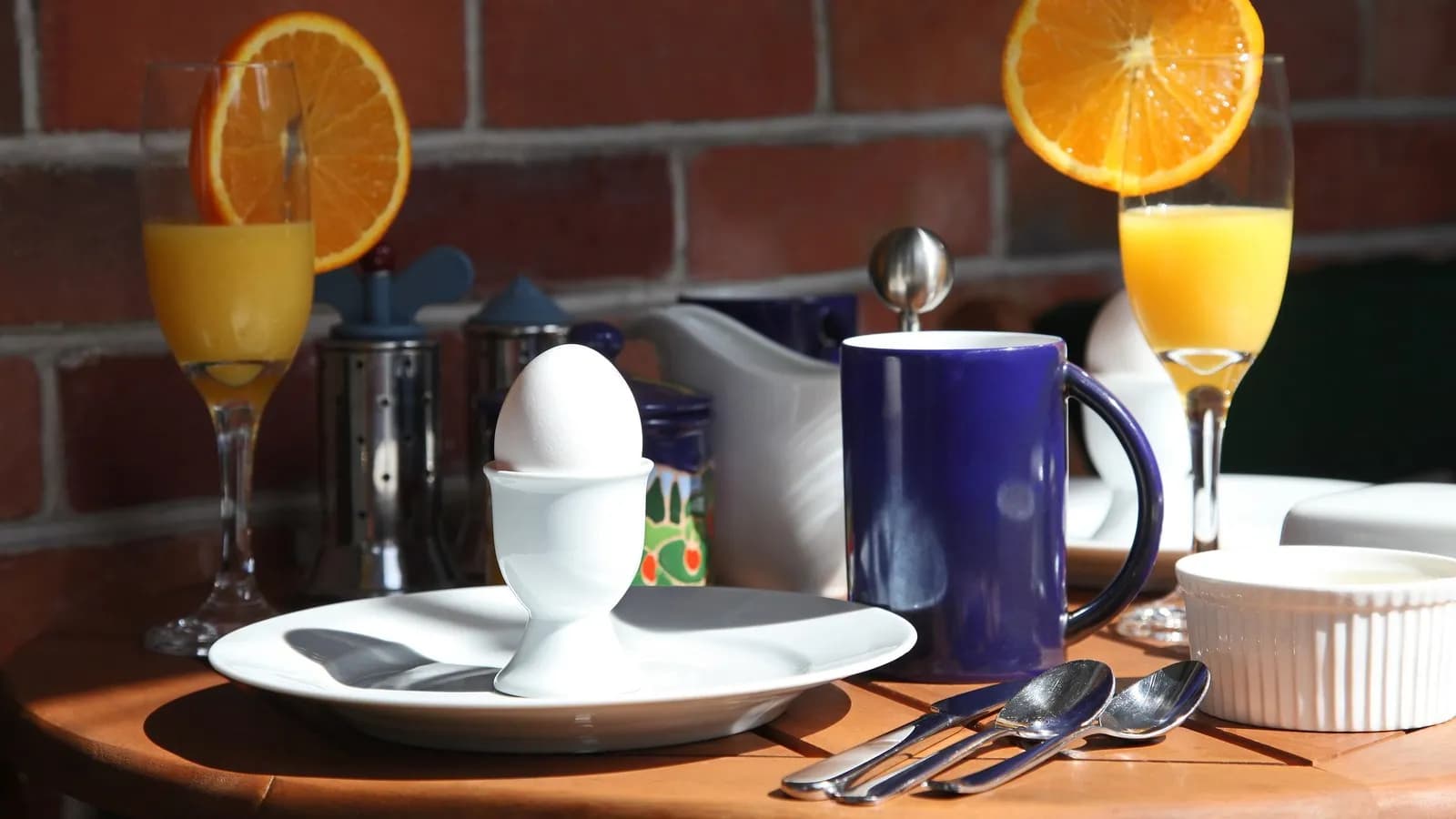 A breakfast table laid with a boiled egg, orange juice and coffee. Early eating windows front-load the day's food to the morning