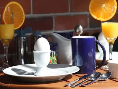 A breakfast table laid with a boiled egg, orange juice and coffee. Early eating windows front-load the day's food to the morning
