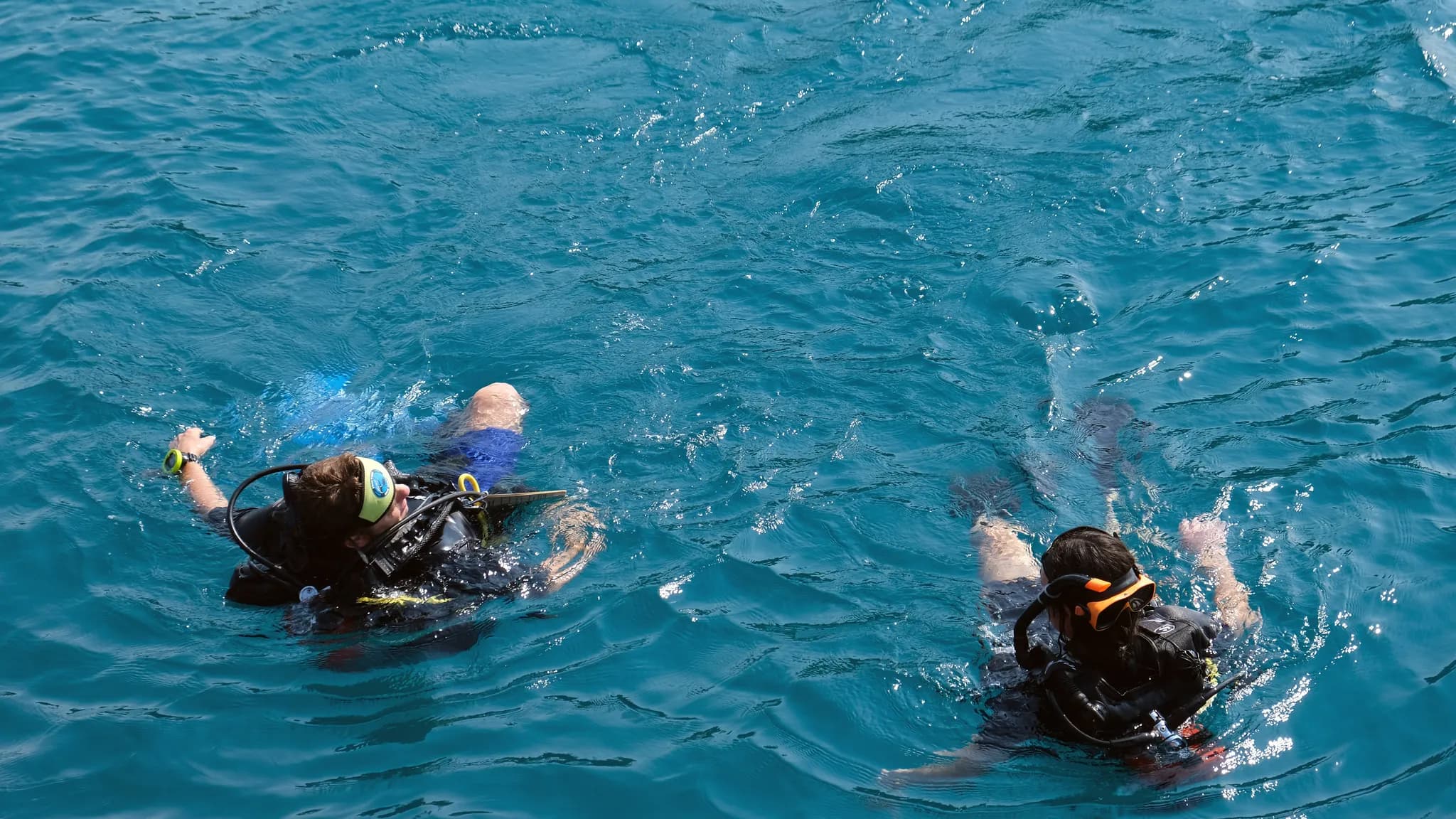 A scuba instructor calmly guiding a new diver during an open-water training session