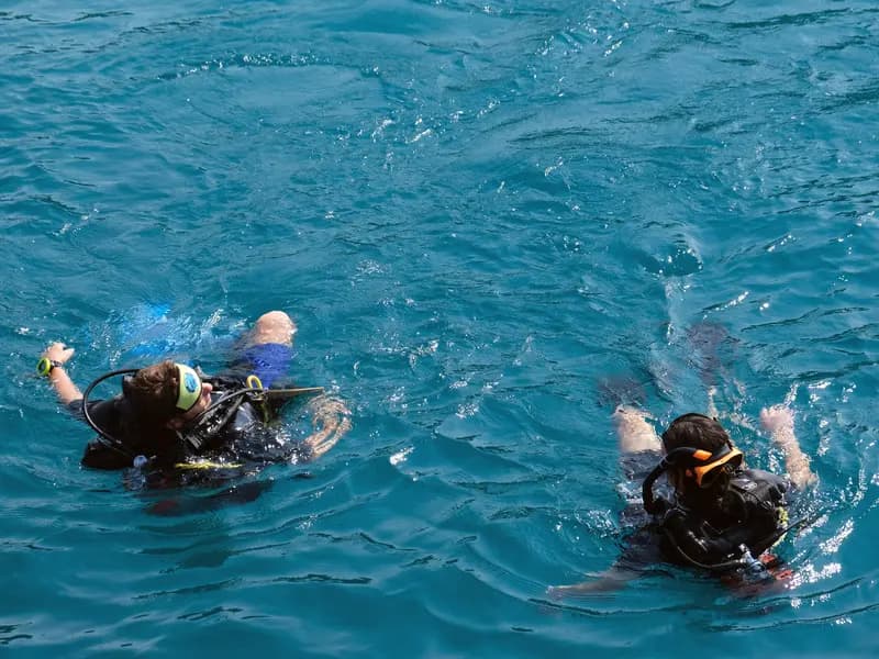 A scuba instructor calmly guiding a new diver during an open-water training session