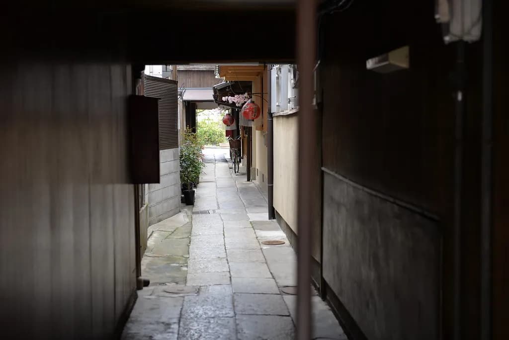 Crowds of tourists walking through a narrow historic street in Kyoto lined with traditional wooden buildings