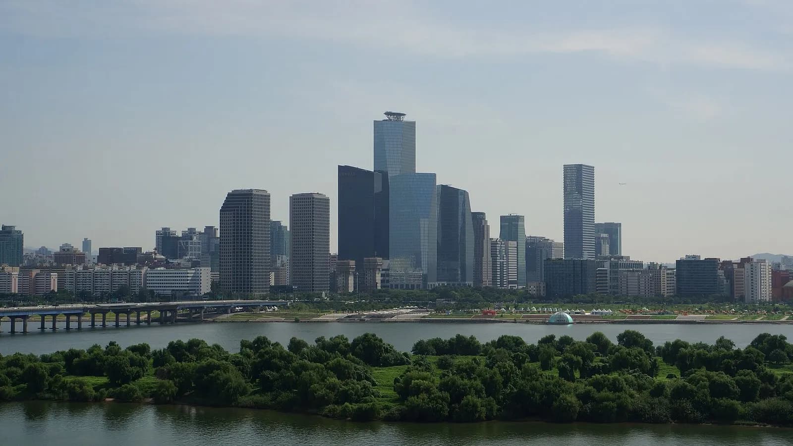 The towers of the Yeouido financial district in Seoul rising above the Han River and the tree-covered Bamseom island under a hazy blue sky, photographed on 10 August 2016, a file photograph of the district and not of Friday's trading