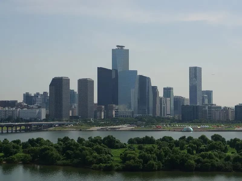 The towers of the Yeouido financial district in Seoul rising above the Han River and the tree-covered Bamseom island under a hazy blue sky, photographed on 10 August 2016, a file photograph of the district and not of Friday's trading