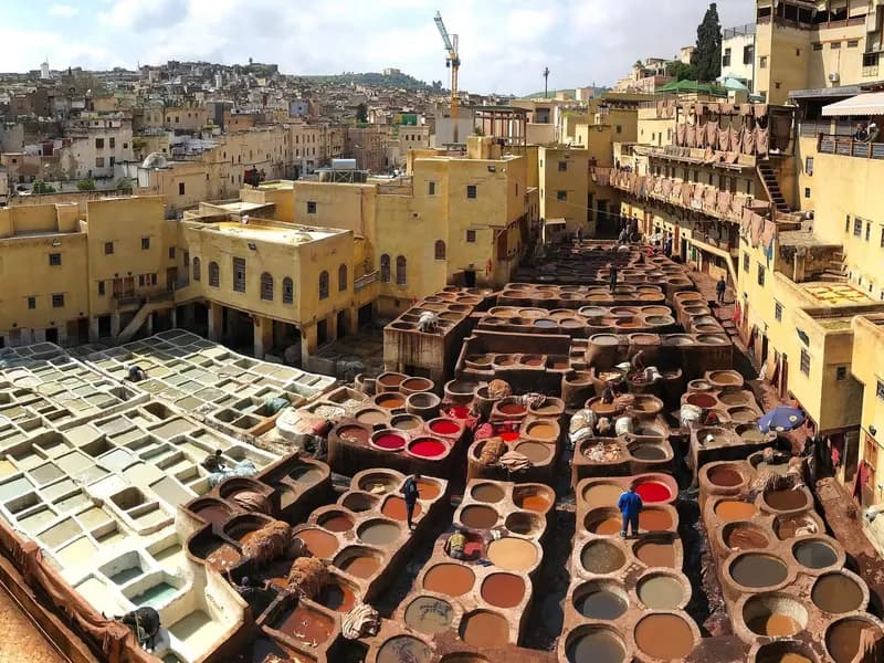 The stone vats of the Chouara tannery in Fez, filled with dye and tanning liquor, seen from the terraces above with the medina beyond