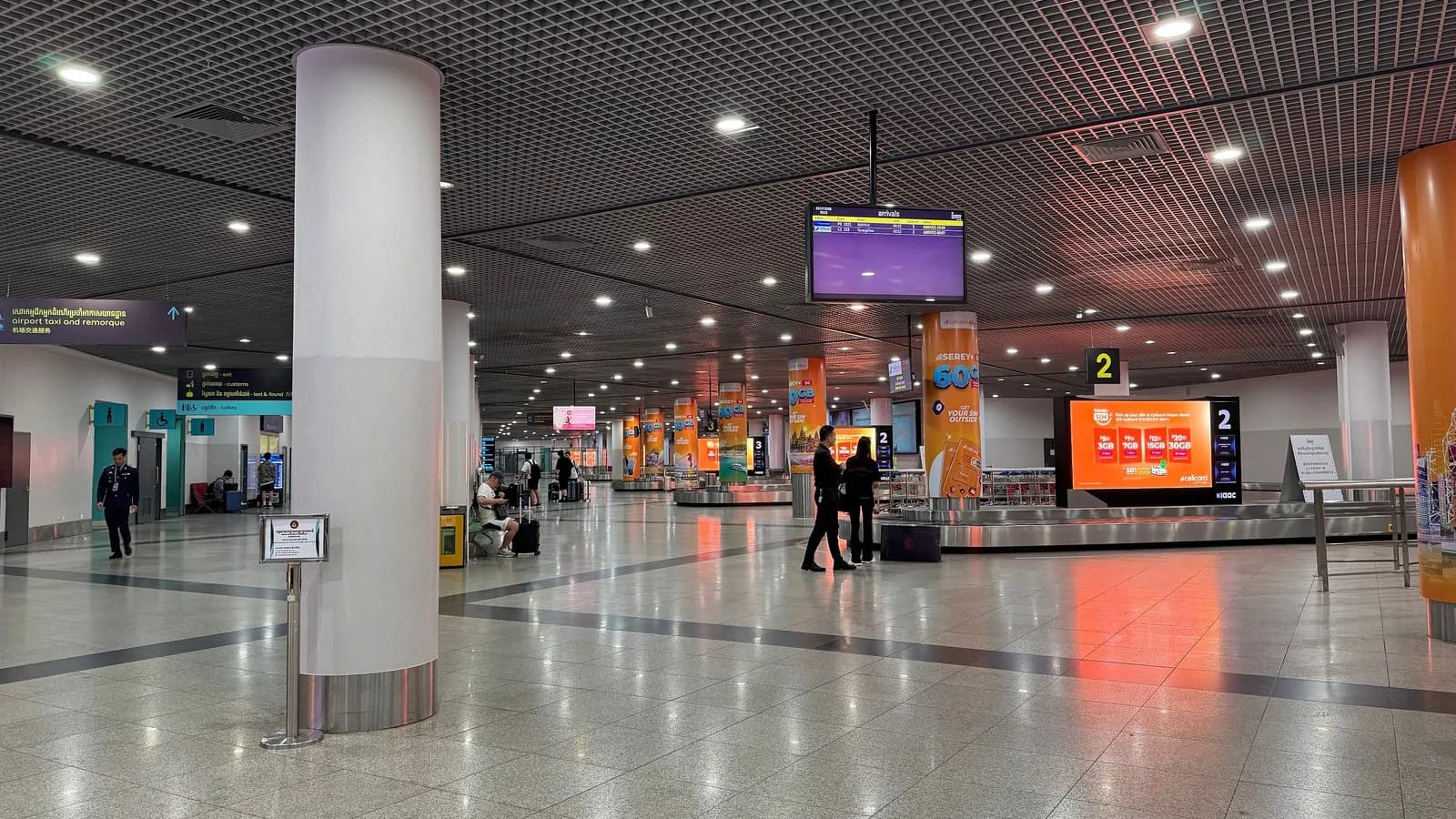 The baggage claim hall at Phnom Penh International Airport, empty belts and a handful of waiting passengers