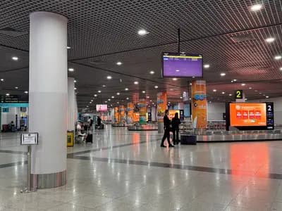 The baggage claim hall at Phnom Penh International Airport, empty belts and a handful of waiting passengers