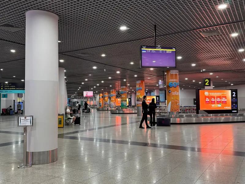 The baggage claim hall at Phnom Penh International Airport, empty belts and a handful of waiting passengers