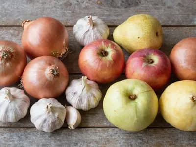 Onions, garlic, apples and pears on a wooden table