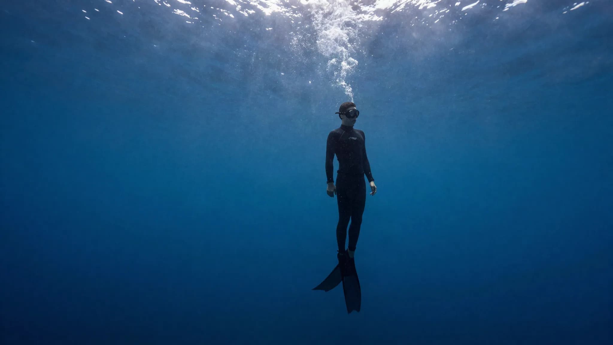 A freediver suspended motionless in deep blue water