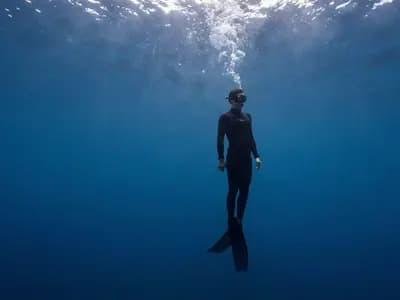 A freediver suspended motionless in deep blue water