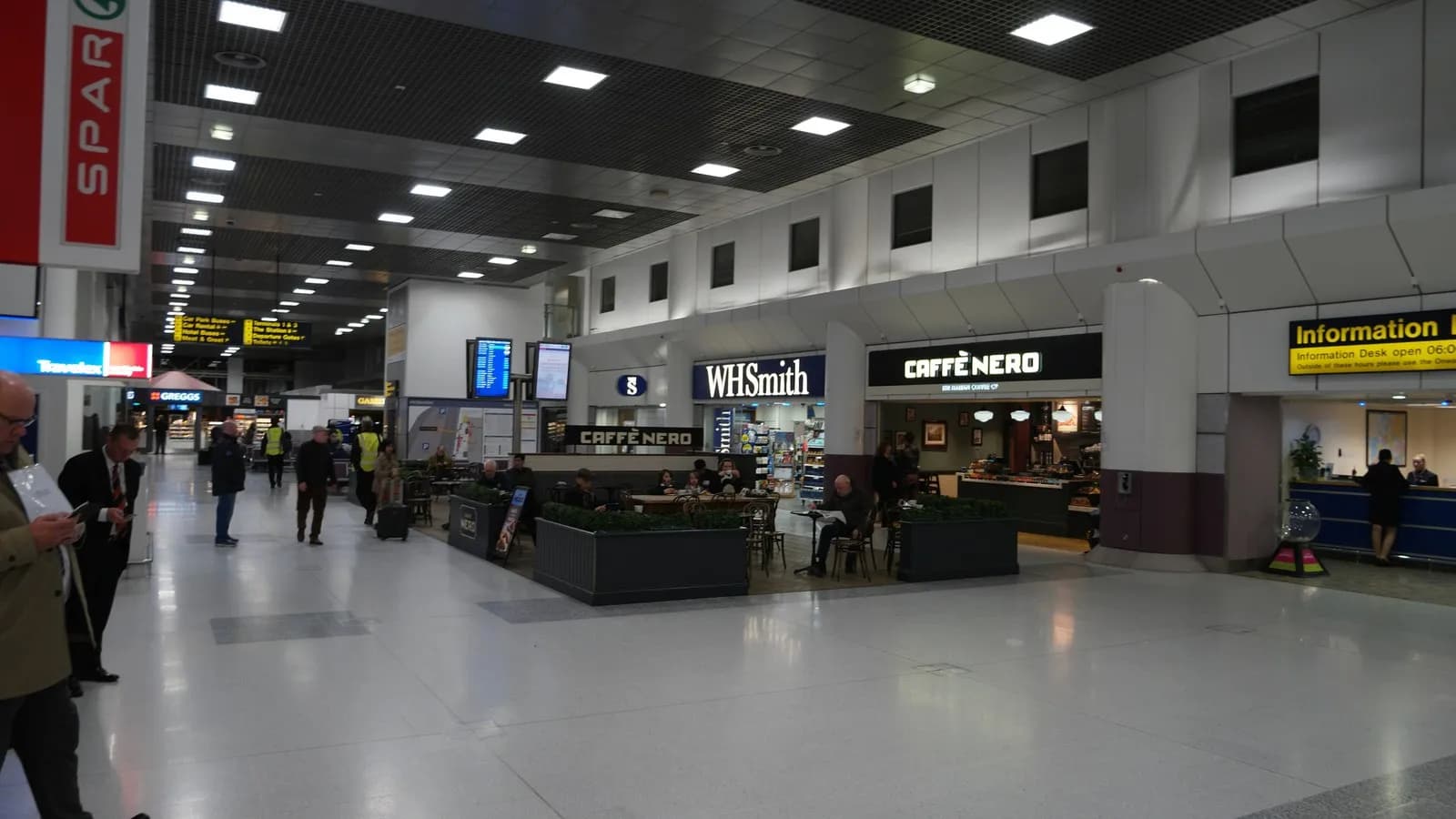 The landside concourse at Manchester Airport Terminal 2, with shops, an information desk and passengers walking through