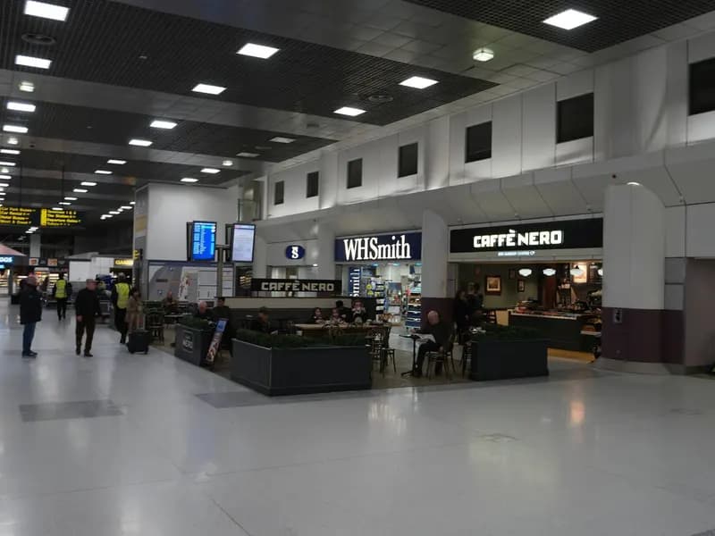 The landside concourse at Manchester Airport Terminal 2, with shops, an information desk and passengers walking through