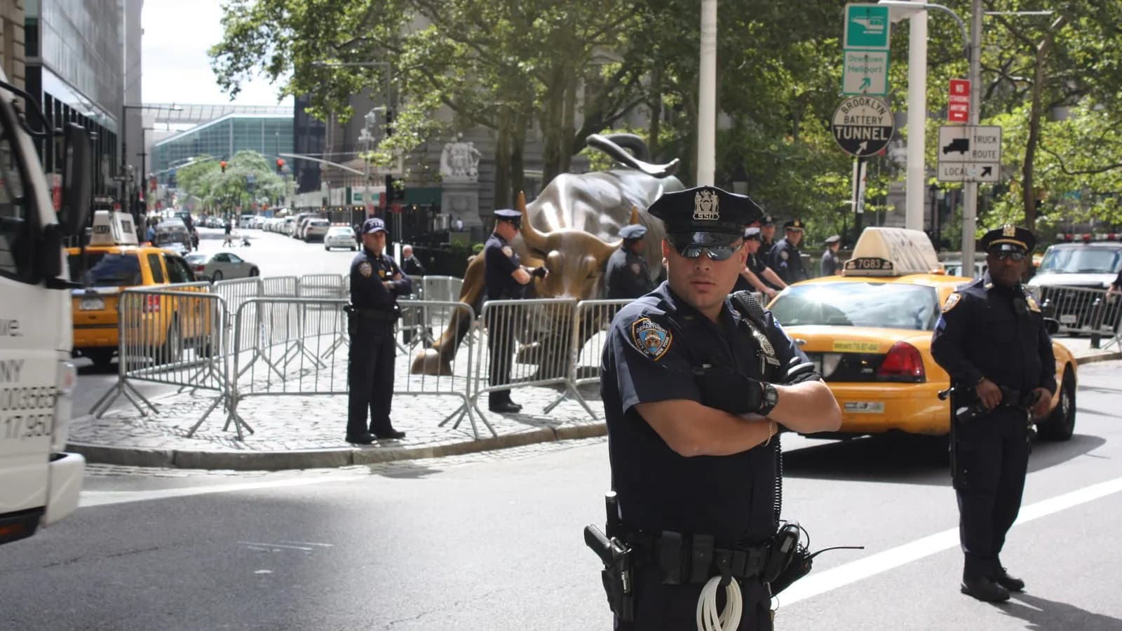 The Charging Bull sculpture on Broadway near Wall Street in New York, with pedestrians passing behind it