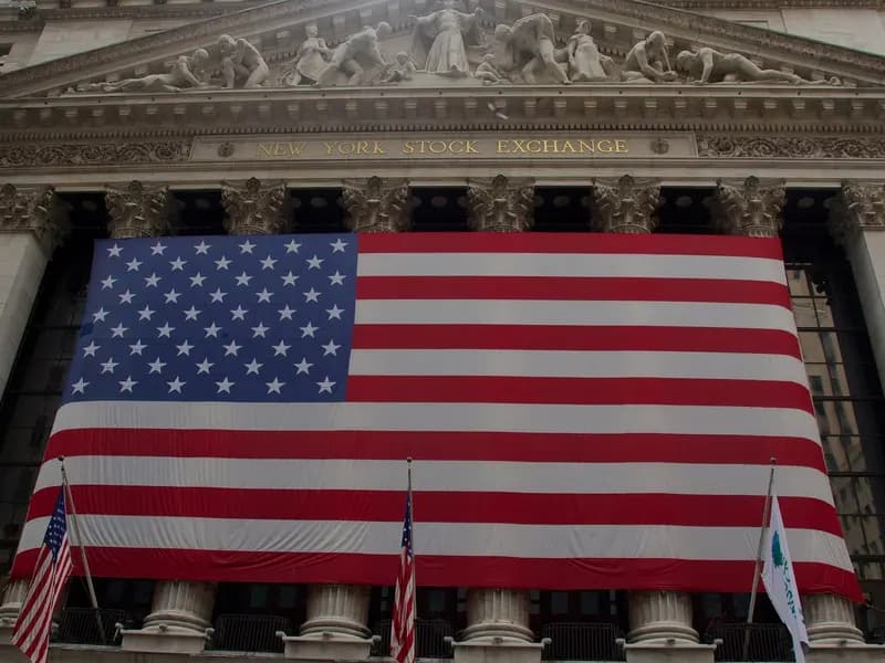 The New York Stock Exchange facade on Wall Street with a large American flag, photographed in July 2012