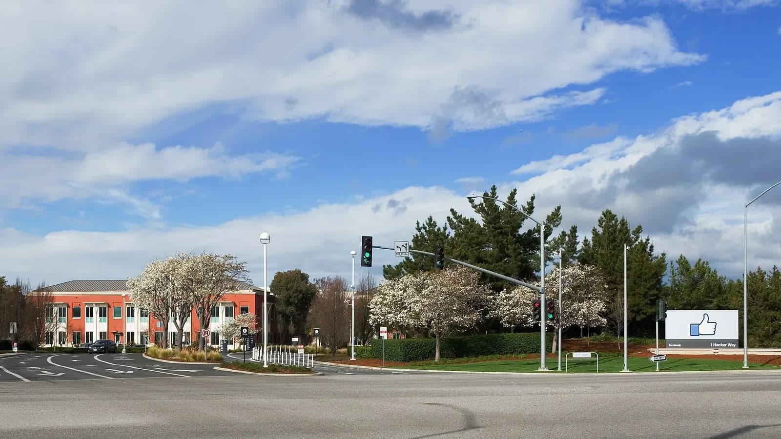 A red brick office building and a thumbs-up sign at the entrance to Meta's headquarters at 1 Hacker Way in Menlo Park, California, with spring blossom and clouds above, photographed on 2 March 2014, a file photograph of the headquarters and not of the share sale