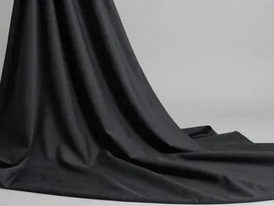 A sculptural drape of matte black fabric lit to show its texture