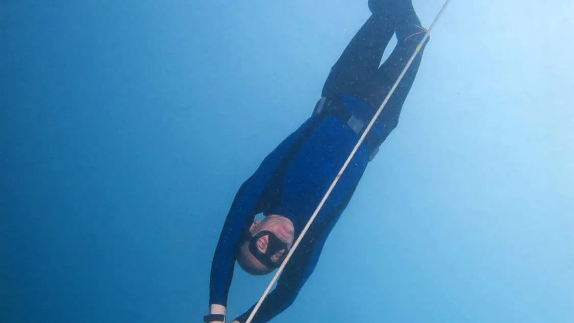 A freediver in a dark wetsuit descending head first along a rope in clear blue water off Moalboal in the Philippines, published in April 2012, a file photograph illustrative of depth freediving and not of the Limassol championships or either record holder