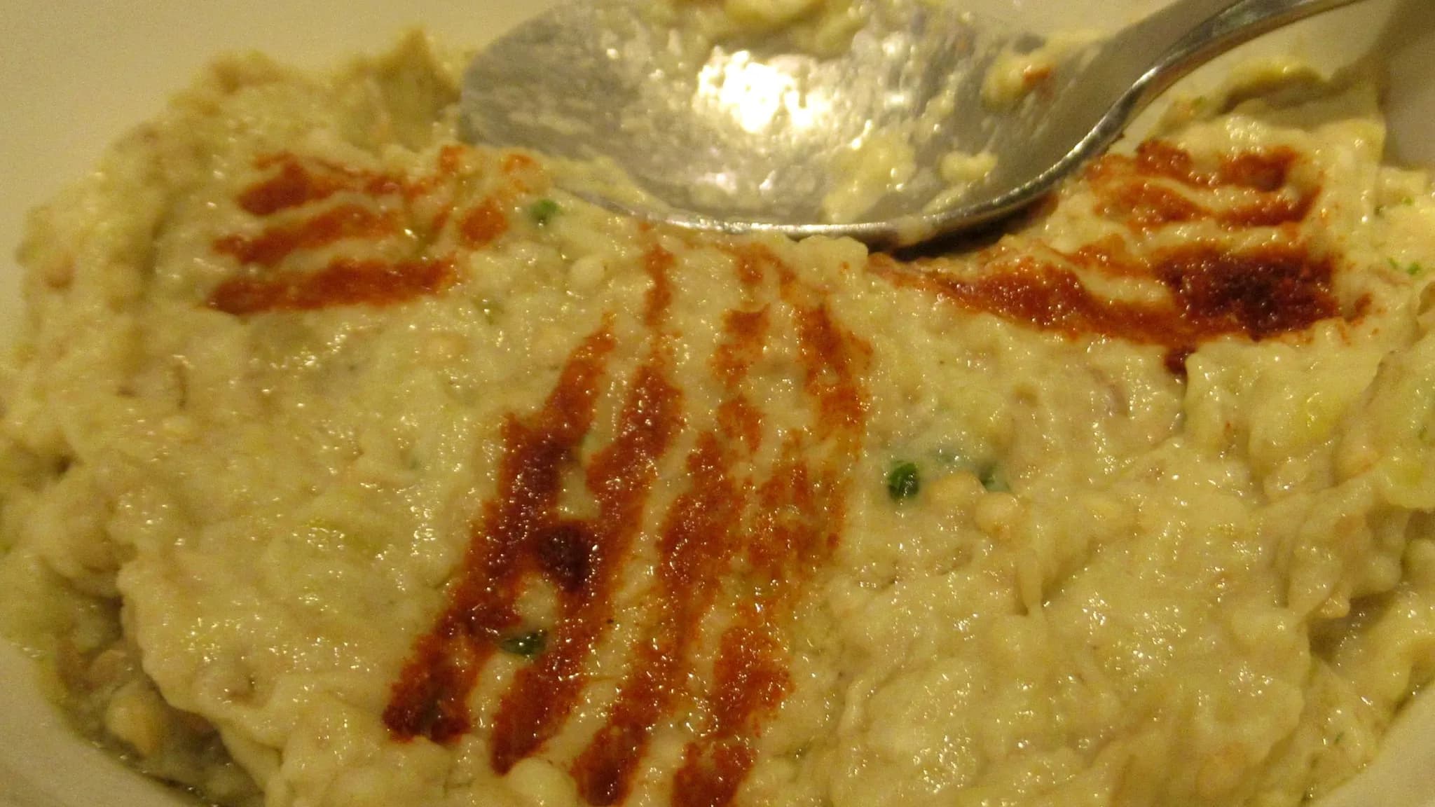 A creamy bowl of moutabal dip drizzled with olive oil and garnished with paprika and parsley