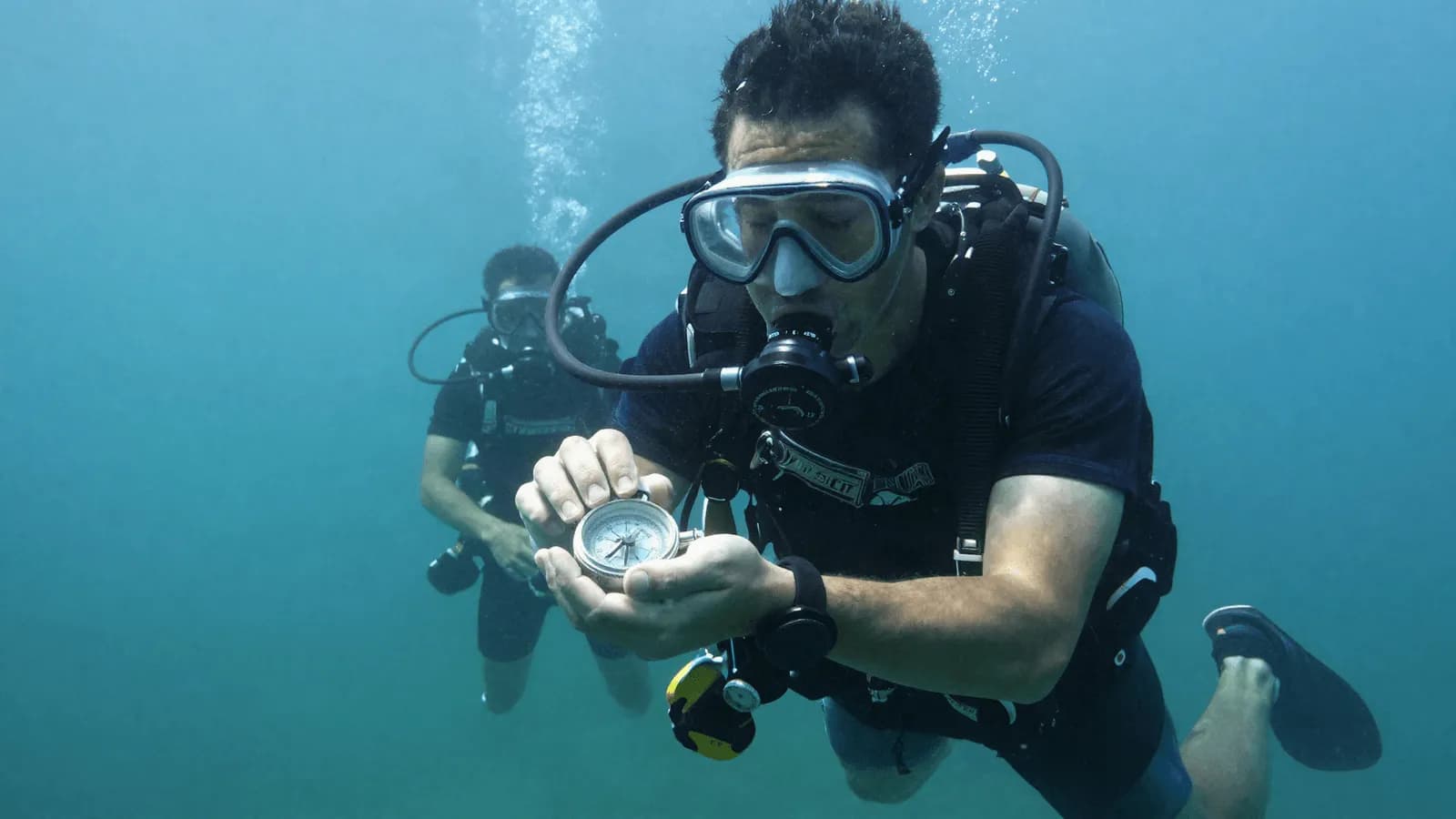 Divers working through a navigation exercise with a compass in open water