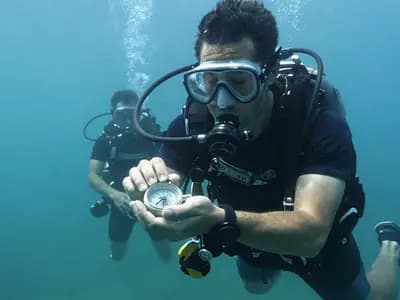Divers working through a navigation exercise with a compass in open water