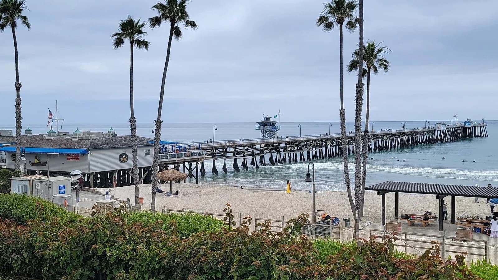 San Clemente Pier in San Clemente, California, with palm trees and a beach in the foreground under an overcast sky, photographed on 10 June 2023, a file photograph of the pier and not of the Norte Fire