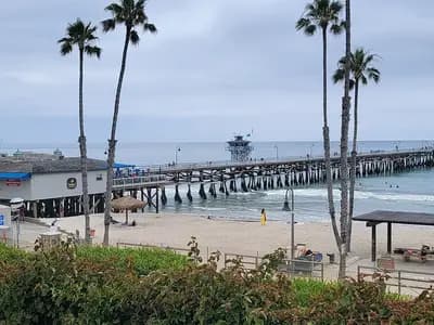 San Clemente Pier in San Clemente, California, with palm trees and a beach in the foreground under an overcast sky, photographed on 10 June 2023, a file photograph of the pier and not of the Norte Fire