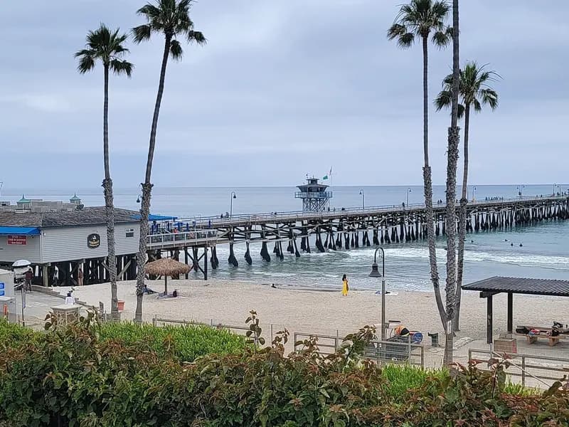 San Clemente Pier in San Clemente, California, with palm trees and a beach in the foreground under an overcast sky, photographed on 10 June 2023, a file photograph of the pier and not of the Norte Fire