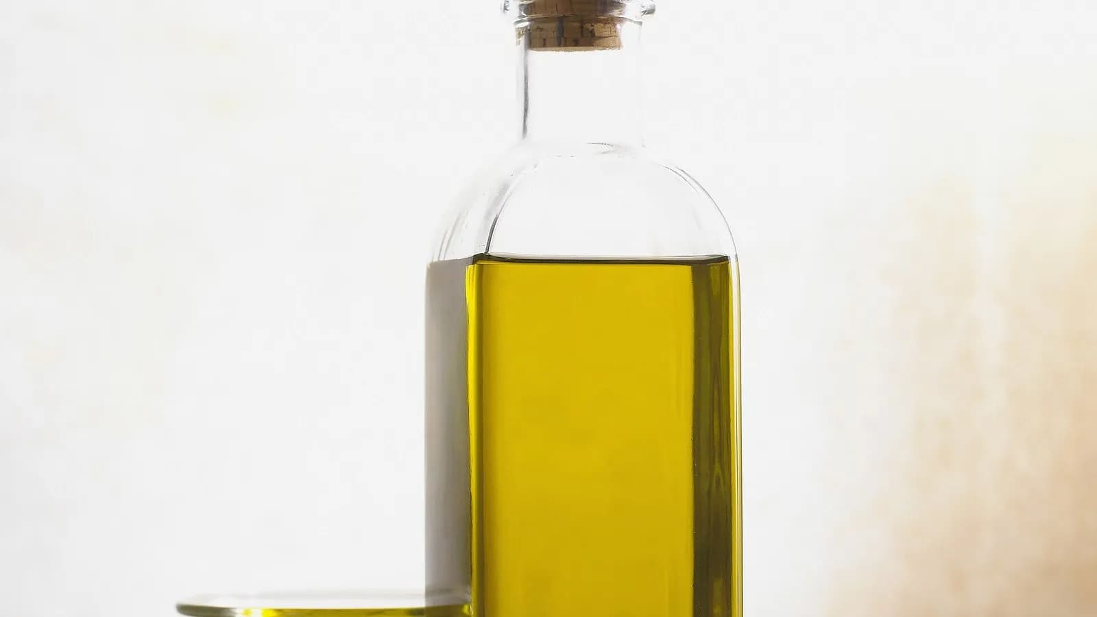 A glass bottle with a cork stopper filled with golden extra-virgin olive oil against a pale background, photographed on 21 June 2005, a file photograph illustrative of olive oil and not of the Kyoto study