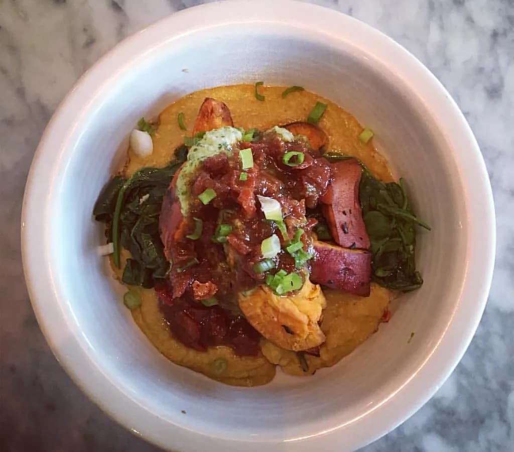 A bowl of creamy red lentil dal with golden tadka-infused oil and fresh cilantro on top, served with rice